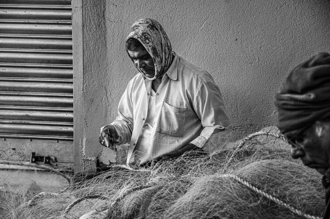 elderly fisherman repairing net